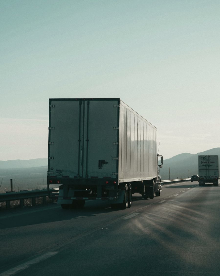 Two semi trucks hauling trailers along a mountain highway