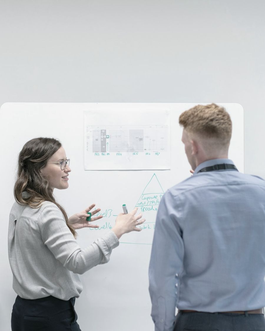 Two colleagues planning at a whiteboard in a bright office